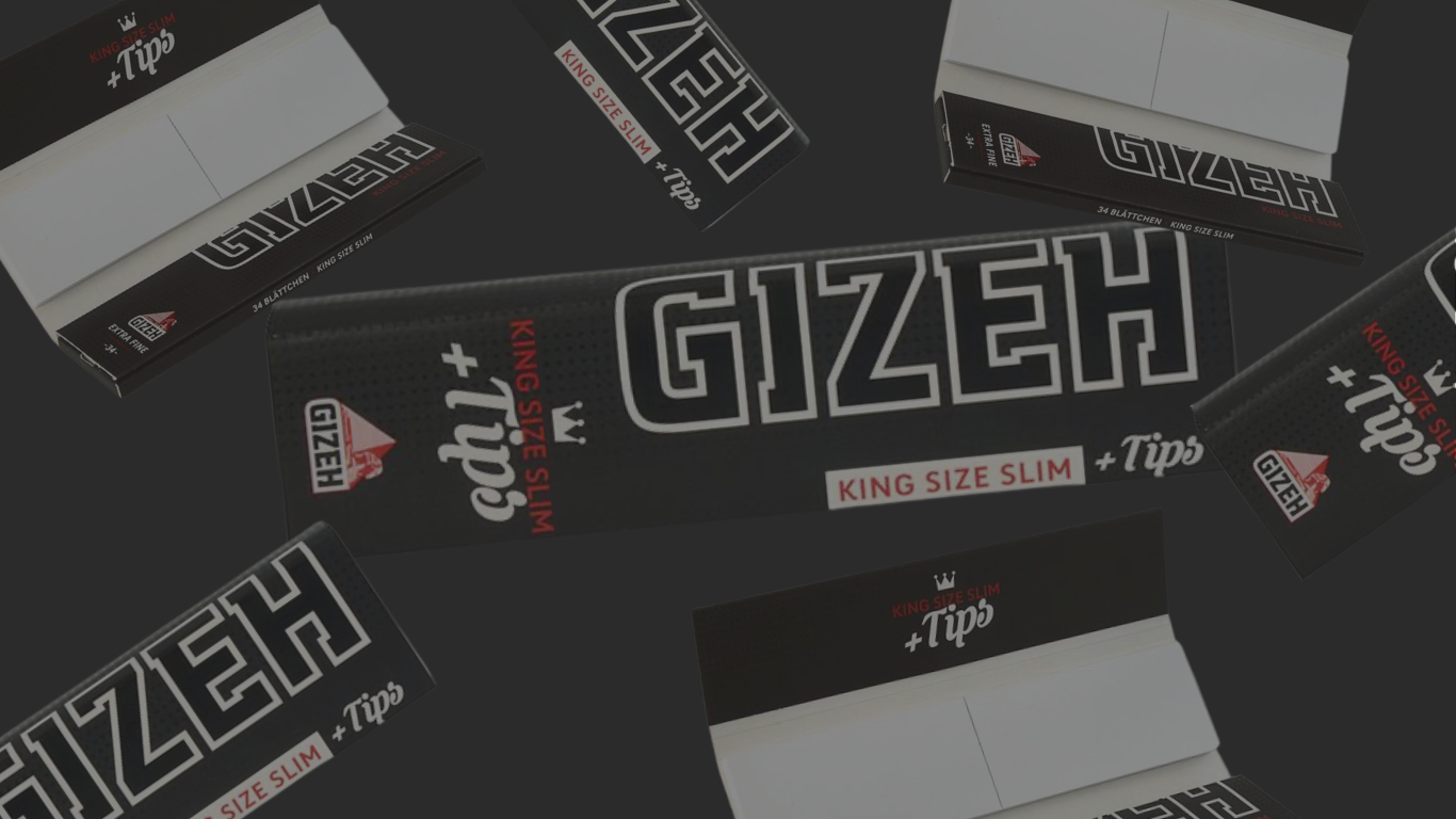 Banner mit mehreren schwarzen GIZEH King Size Slim + Tips Packungen auf dunkelgrauem Hintergrund, zentral groß das „GIZEH“-Logo, rundherum weitere Packungen teils geöffnet mit sichtbaren Tips/Papieren.