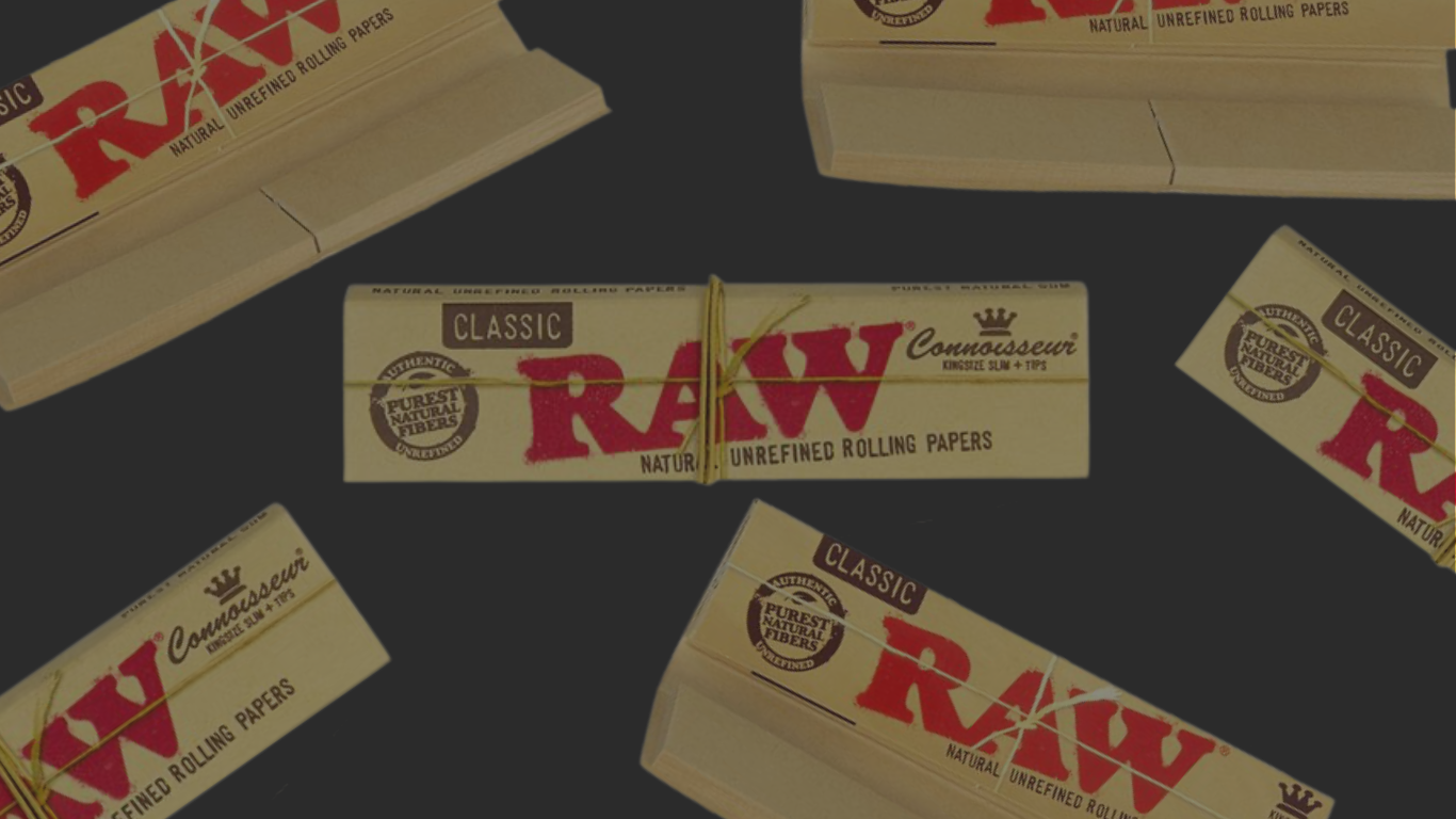 Banner mit RAW Classic King Size Longpapes inkl. Tips: mehrere braune RAW-Classic-Packungen mit rotem RAW-Logo und „Classic“-Label auf dunkelgrauem Hintergrund, eine große Packung mittig, weitere Packungen schräg angeschnitten rundherum.
